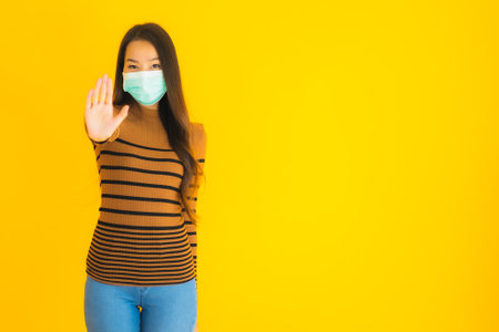 Portrait beautiful young asian woman with mask in many action for protect from coronaviruse or covid19 on yellow isolated backgroundの写真素材