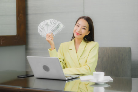 Portrait beautiful young asian woman use computer laptop with smart mobile phone on working table at interior roomの写真素材
