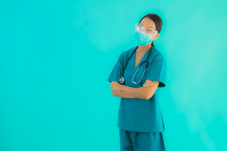 Portrait beautiful young asian doctor woman with mask and eyeglassses for protect from covid19 or coronavirus on blue isolated backgroundの写真素材