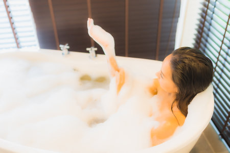 Portrait beautiful young asian woman happy smile relax take a bath in bathtub of bathroom interiorの写真素材
