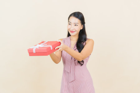 Portrait beautiful young asian woman smile with red gift box on color background