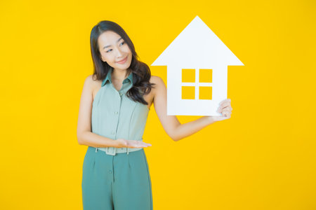 Portrait beautiful young asian woman with house or home paper sign on color backgroundの写真素材