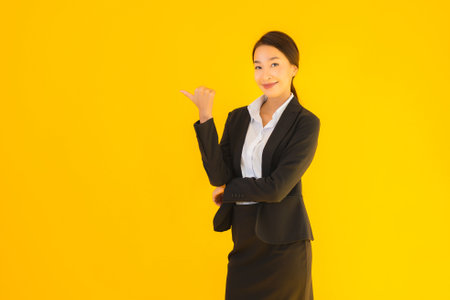 Beautiful portrait young business asian woman happy smile in many action on yellow isolated backgroundの写真素材