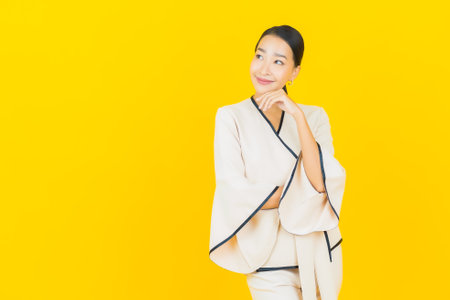 Portrait beautiful young business asian woman with smile and action yellow backgroundの写真素材