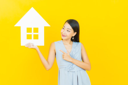 Portrait beautiful young asian woman with house or home paper sign on color backgroundの写真素材