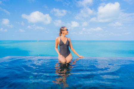 Portrait beautiful young asian woman relax smile leisure around outdoor swimming pool in resort hotel with sea ocean viewの写真素材