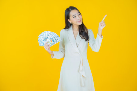 Portrait beautiful young asian woman smile with a lot of cash and money on color backgroundの写真素材