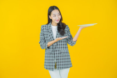 Portrait beautiful young asian woman smile with empty plate dish on color backgroundの写真素材