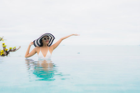 Portrait beautiful young asian woman smile relax and leisure around outdoor swimming pool in resortの写真素材