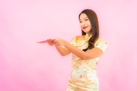 Portrait beautiful young asian woman with red envelopes in chinese new year concept on pink backgroundの写真素材