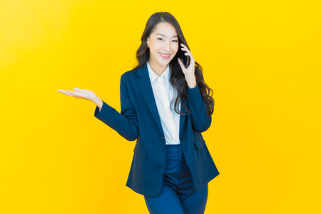 Portrait beautiful young asian woman smile with smart mobile phone on color backgroundの写真素材