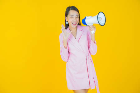 Portrait beautiful young asian woman smile with megaphone on color backgroundの写真素材