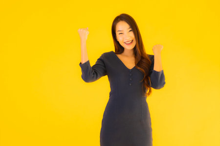 Portrait beautiful young asian woman with action on isolated yellow backgroundの写真素材