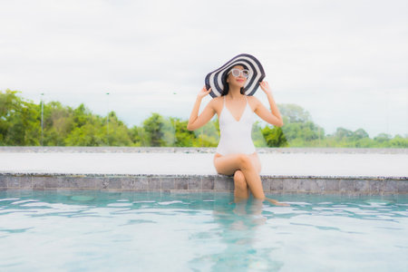 Portrait beautiful young asian woman smile relax and leisure around outdoor swimming pool in resortの写真素材