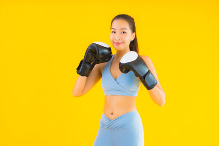 Portrait beautiful young asian woman wear sportwear with boxing on yellow isolated backgroundの写真素材
