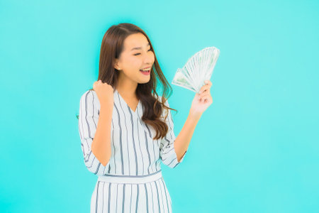 Portrait beautiful young asian woman with a lot of cash and money on blue backgroundの写真素材