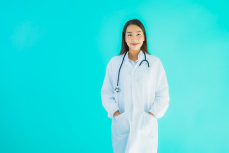 Portrait beautiful young asian doctor woman with stethoscope for use in clinic or hospital on blue isolated backgroundの写真素材