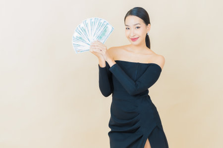 Portrait beautiful young asian woman smile with a lot of cash and money on color backgroundの写真素材