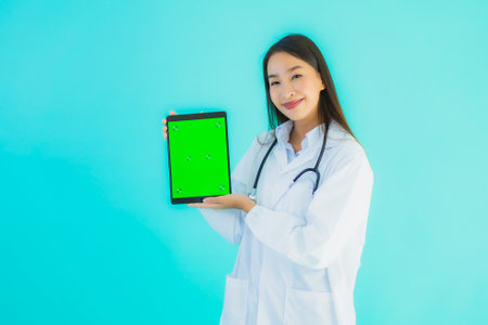 Portrait beautiful young asian doctor woman with stethoscope and smart tablet for use in hospital and clinic on blue isolated backgroundの写真素材