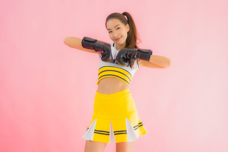 Portrait beautiful young asian woman cheerleader with boxing action on pink isolated background