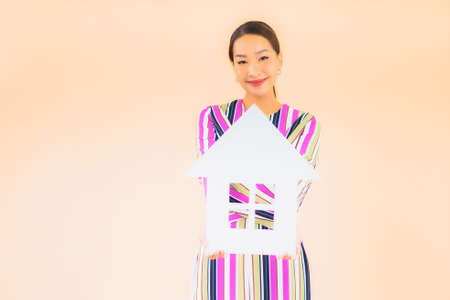 Portrait beautiful young asian woman with home or house sign paper on color backgroundの写真素材