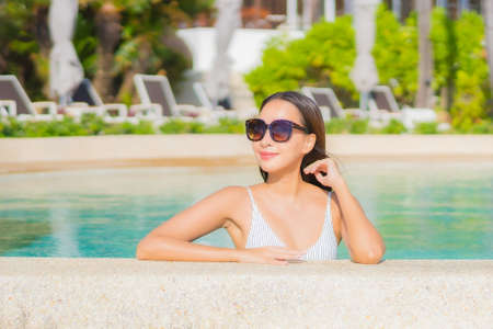 Portrait beautiful young asian woman relax happy smile around outdoor swimming pool in hotel resort...