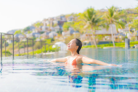 Portrait beautiful young asian woman relax smile leisure around outdoor swimming pool in resort hotel with sea ocean viewの写真素材