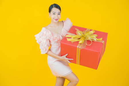 Portrait beautiful young asian woman smile with red gift box on color backgroundの写真素材