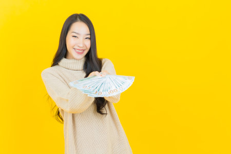 Portrait beautiful young asian woman smile with a lot of cash and money on color backgroundの写真素材