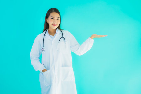 Portrait beautiful young asian doctor woman with stethoscope for use in clinic or hospital on blue isolated backgroundの写真素材