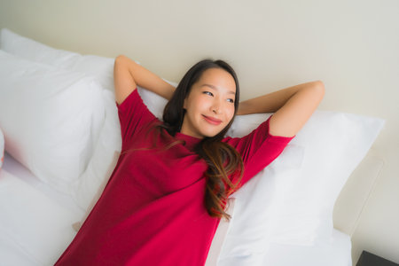 Portrait beautiful young asian women smile happy on bed in bedroom interiorの写真素材