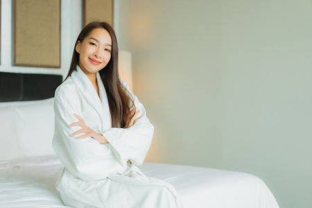 Portrait beautiful young asian woman smile relax on bed in bedroom interiorの写真素材