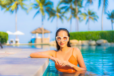 Portrait beautiful young asian woman relax smile leisure around outdoor swimming pool with sea ocean...