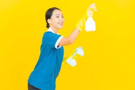 Portrait beautiful young asian woman maid and housekeeping smile with action on yellow color backgroundの写真素材
