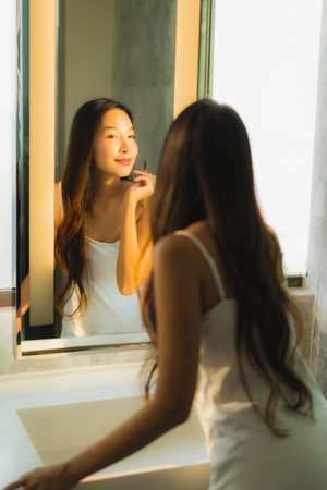 Portrait beautiful young asian woman make up with cosmetic powder and lipstick on her face facial in bathroom interiorの写真素材