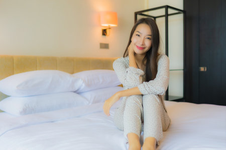 Portrait beautiful young asian woman smile happy relax on bed in bedroom interiorの写真素材