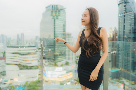 Portrait beautiful young asian woman relax enjoy restaurant on the rooftop around city viewの写真素材