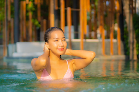 Portrait beautiful young asian woman relax smile enjoy leisure around swimming pool in hotel resortの写真素材