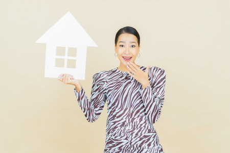 Portrait beautiful young asian woman with house or home paper sign on color backgroundの写真素材