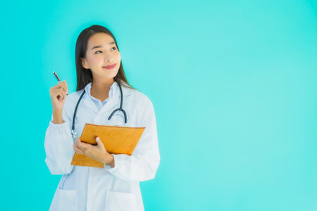 Portrait beautiful young asian doctor woman with empty card billboard banner on blue isolated backgroundの写真素材
