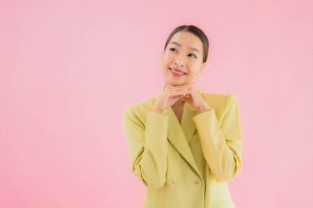 Portrait beautiful young asian business woman smile in action on pink color backgroundの写真素材