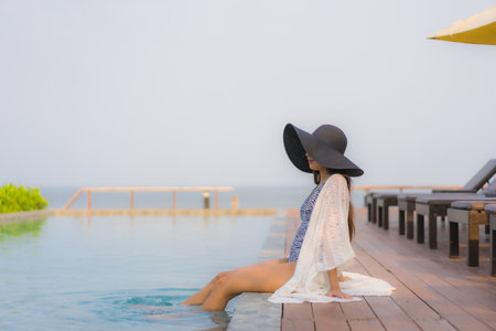 Portrait young asian woman happy smile relax around outdoor swimming pool in hotel resort for travel vacationの写真素材
