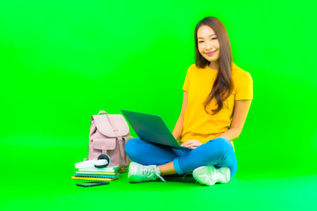 Portrait beautiful young asian woman use computer laptop on green isolated backgroundの写真素材