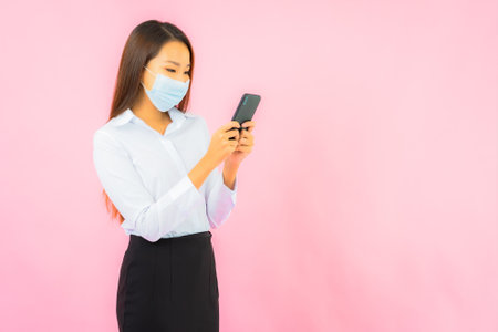 Portrait beautiful young asian woman wear mask for protect from covid19 and coronavirus on pink backgroundの写真素材
