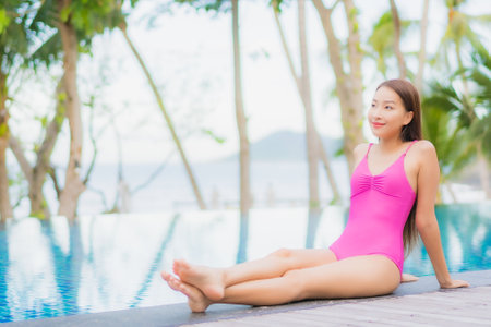 Portrait beautiful young asian woman smile relax around outdoor swimming pool in resort hotel on holiday vacation travel tripの写真素材