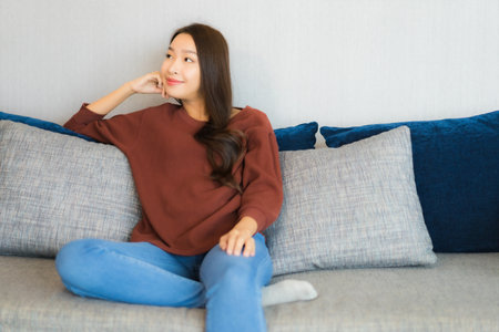 Portrait beautiful young asian woman relax smile on sofa in living room interiorの写真素材