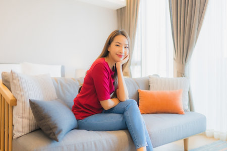 Portrait beautiful young asian woman relax smile on sofa in living area at bedroom interiorの写真素材