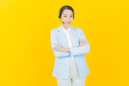 Portrait beautiful young asian woman with call center customer care service center on yellow color backgroundの写真素材