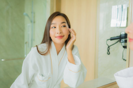 Portrait beautiful young asian woman check up face in bathroom interiorの写真素材