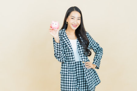Portrait beautiful young asian woman with piggy bank on color backgroundの写真素材